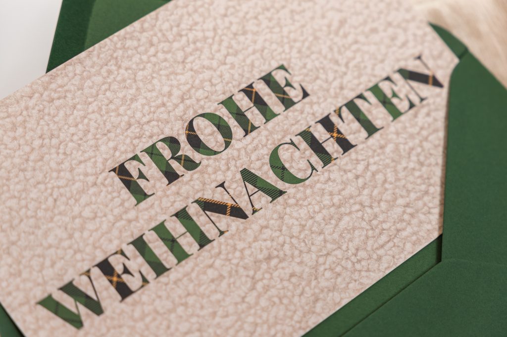 Coole Weihnachtskarte mit großem Schriftzug „Frohe Weihnachten“ in Grün auf Bouclé-Optik
