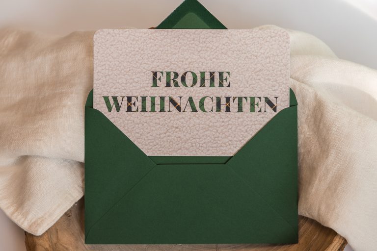 Coole Weihnachtskarte mit großem Schriftzug „Frohe Weihnachten“ in Bouclé-Optik und grünem Umschlag