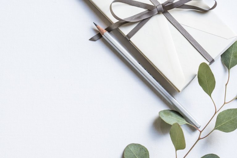 Weiße Umschläge mit Schleife, Bleistift und Eukalyptuszweig – Weihnachtskarten schreiben