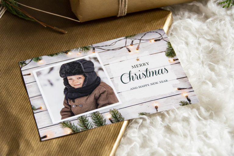 Weihnachtskarte mit Kinderfoto im Winter, Merry-Christmas-Schriftzug und Lichterkette
