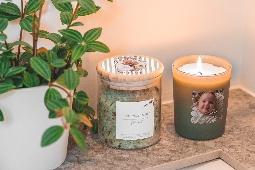 Glas mit Badesalz und Duftkerze mit Foto neben einer Grünpflanze